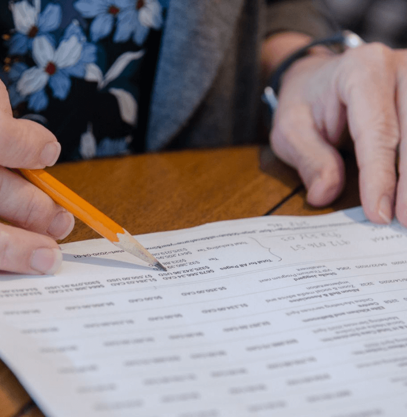 Person reviewing a printed financial document with data, representing detailed financial analysis and bookkeeping services.